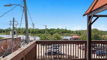 A wooden deck with a railing overlooking a parking area and a body of water.
