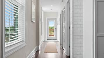 A hallway with a wooden floor, white walls, and a door leading to a balcony.