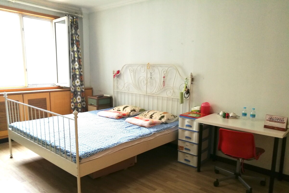A bedroom with a bed, a desk, and a chair.