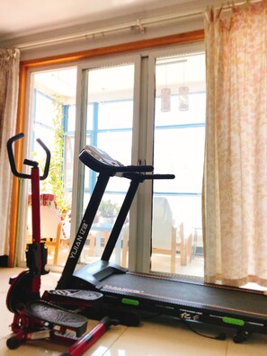 A treadmill in a room with a large window and a view of a balcony. - Golden guesthouse (Beijing)