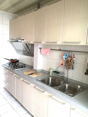 A modern kitchen with stainless steel appliances, a double sink, and a hanging utensil rack. - Golden guesthouse (Beijing)