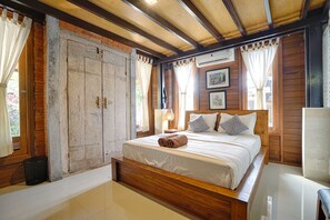Een slaapkamer met een houten frame, een groot bed, een nachtkastje en een raam met gordijnen.