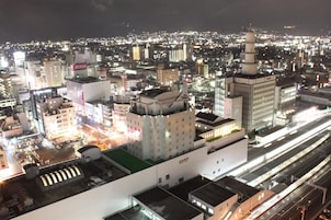 Un paisaje urbano nocturno con edificios iluminados y una torre destacada.