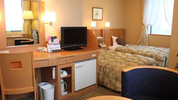 Habitación de hotel con cama, escritorio con televisor, mini refrigerador, cesto de basura y una silla.