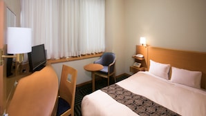 A hotel room with a bed, a desk with a lamp, a chair, a TV, a bedside table with a phone, and a window with curtains. - Yamagata Eki Nishiguchi Washington Hotel (Yamagata)