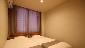 Habitación de hotel con dos camas, cabecero de madera, aire acondicionado de pared y ventana con cortinas.