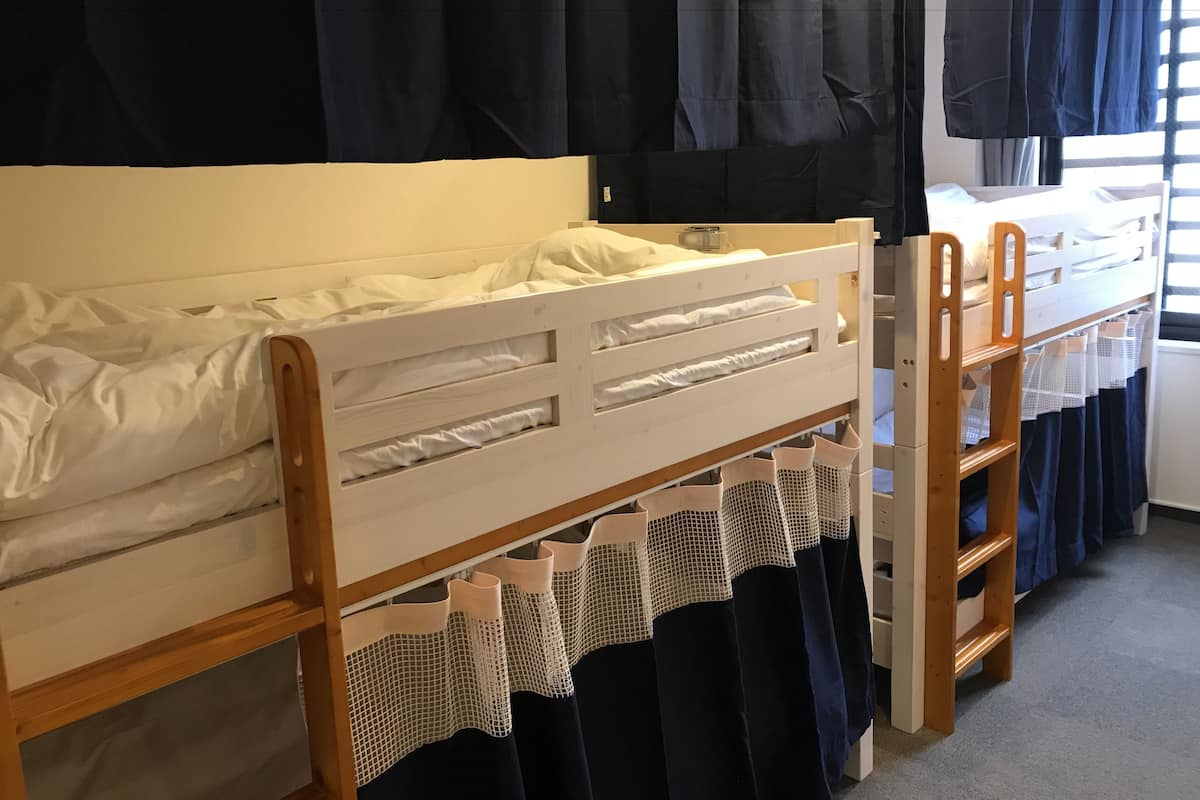 Ein Etagenbett mit Holzrahmen, weißer Bettwäsche und einem Netzvorhang.