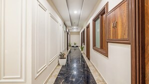 A hallway with white walls, wooden doors, and a marble floor. - Treebo JD Residency Mohali (Mohali)