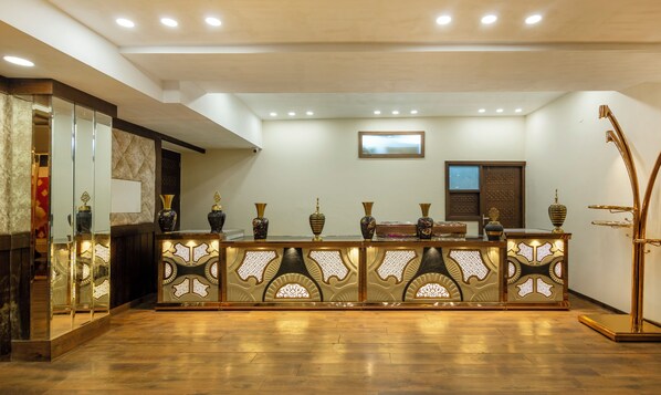 Un área de recepción con un mostrador de madera, jarrones decorativos y un cuadro en la pared.