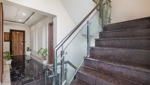 A modern interior with a marble staircase, glass railings, and potted plants. - Treebo JD Residency Mohali (Mohali)