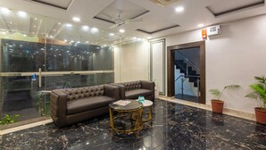 A modern lobby with a leather sofa, a glass partition, a marble floor, and a staircase. - Treebo JD Residency Mohali (Mohali)