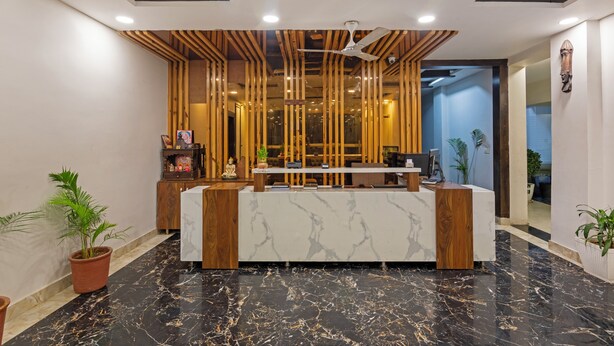A reception desk with a marble top, wooden accents, and a ceiling fan. - Treebo JD Residency Mohali (Mohali)