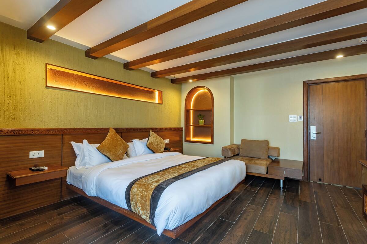 A hotel room with a large bed, wooden headboard, and a built-in bench.