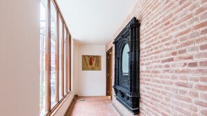 Un pasillo con ventanas amplias, pared de ladrillo y un marco negro decorativo.