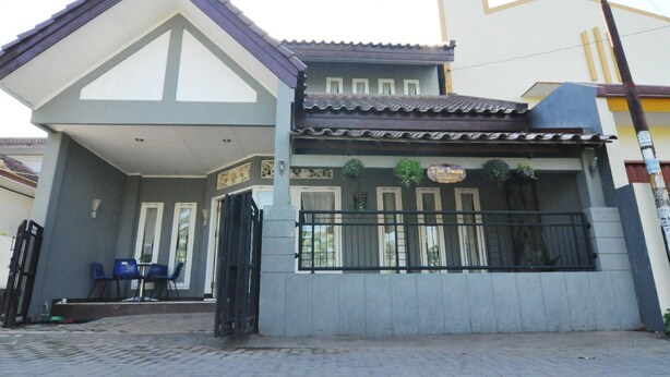 A two-story building with a balcony, a covered entrance, and a small outdoor seating area with chairs. - D'Java Homestay Unit Ambarrukmo 2 By The Grand Java (Depok)