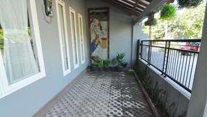 A covered balcony with patterned flooring, potted plants, and a decorative wall mural. - D'Java Homestay Unit Ambarrukmo 2 By The Grand Java (Depok)