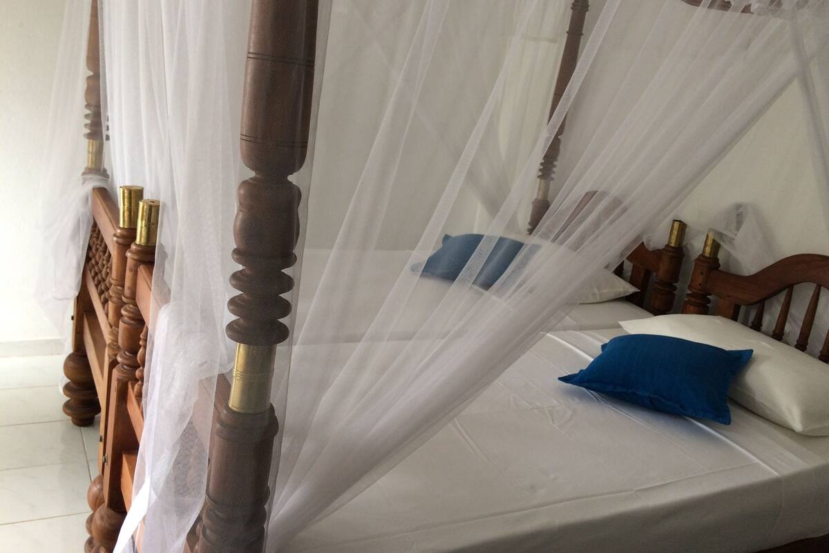 Un lit avec une couvre-lit blanche, un oreiller bleu et une tête de lit en bois.