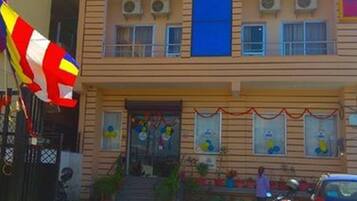 Un edificio de varios pisos con fachada plana, unidades de aire acondicionado y una bandera.
