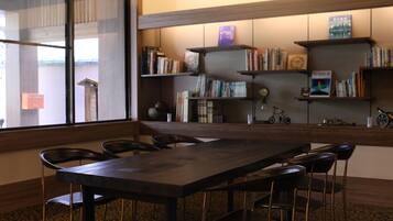 Une bibliothèque moderne dotée d’une grande table et de chaises, d’étagères et d’une horloge.