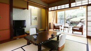Una habitación japonesa tradicional con suelo de tatami, una mesa de madera y un televisor.
