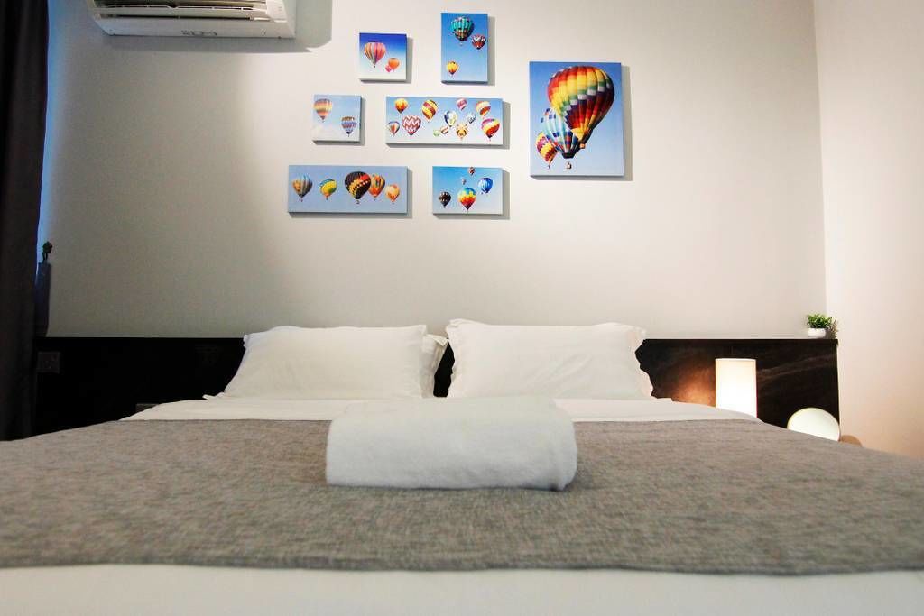 A hotel room with a neatly made bed, a large window, and a wall decorated with multiple framed pictures of hot air balloons.
