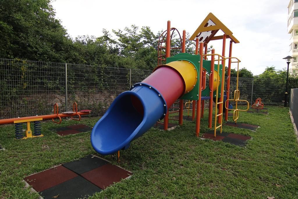 A playground with a multi-colored slide, climbing structures, and a fenced area.