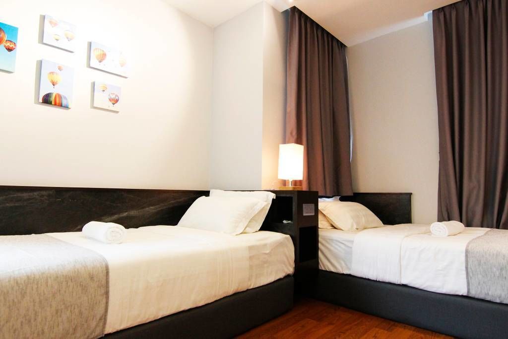 Une chambre d’hôtel avec deux lits, une table de chevet, une lampe et des œuvres d’art accrochées au mur.