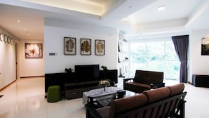 A modern living room with a flat-screen TV, a sofa, a coffee table, and artwork on the walls. - Sabah Luxury Cozy Family Suite (Kota Kinabalu)