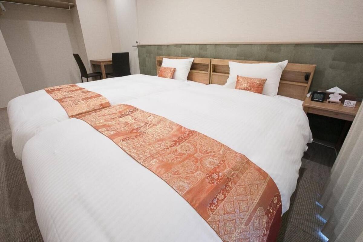 A hotel room with a large bed, a wooden headboard, a bedside table, and a chair.