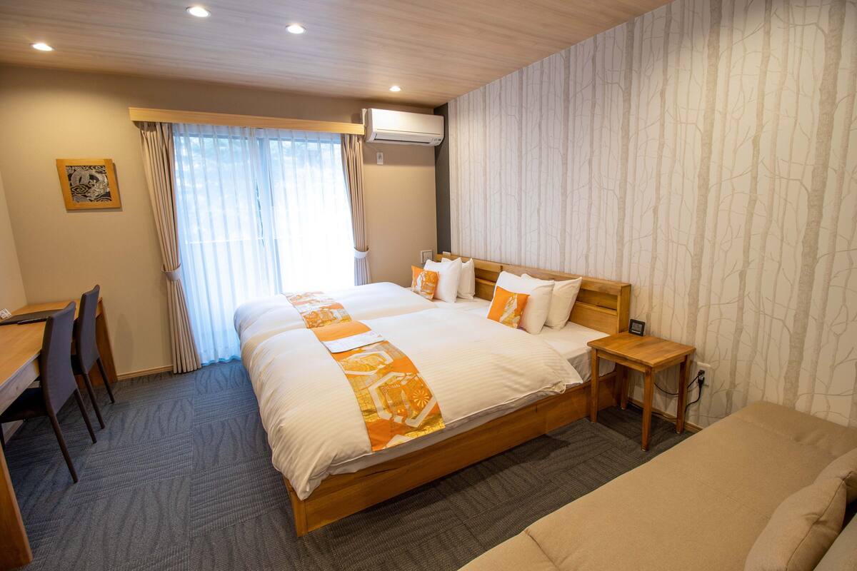 A hotel room with a large bed, a desk, and chairs.