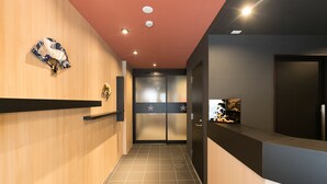 A modern hallway with wooden paneling, a red ceiling, and a tiled floor. There are two doors with frosted glass panels and a small shelf with decorative items. - Stay SAKURA Kyoto Ryu (Kyoto)