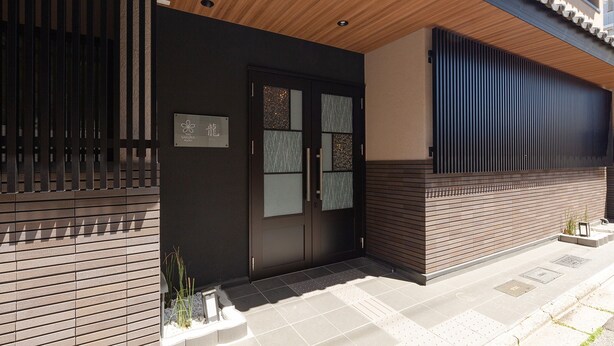A modern building with a dark facade, wooden ceiling, and a tiled entrance area. - Stay SAKURA Kyoto Ryu (Kyoto)