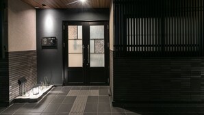 A modern entrance with a dark facade, a wooden ceiling, and a tiled floor. - Stay SAKURA Kyoto Ryu (Kyoto)