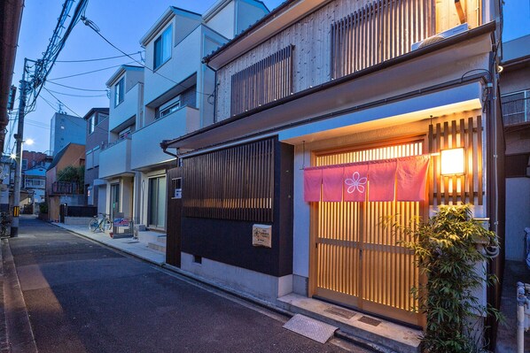 A traditional Japanese building with a wooden gate and a signboard.