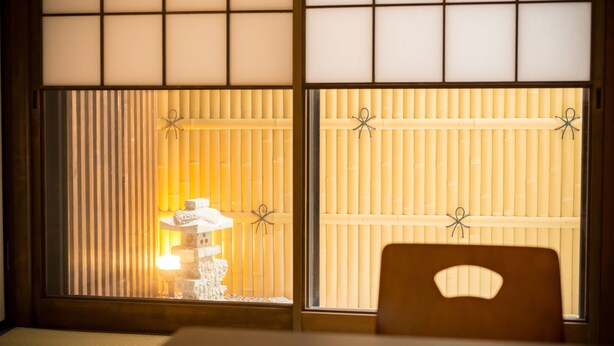 A traditional Japanese room with tatami flooring, a low table with a decorative item, and shoji screens with a warm light source behind them. - Stay SAKURA Kyoto To-ji Machiya (Kyoto)