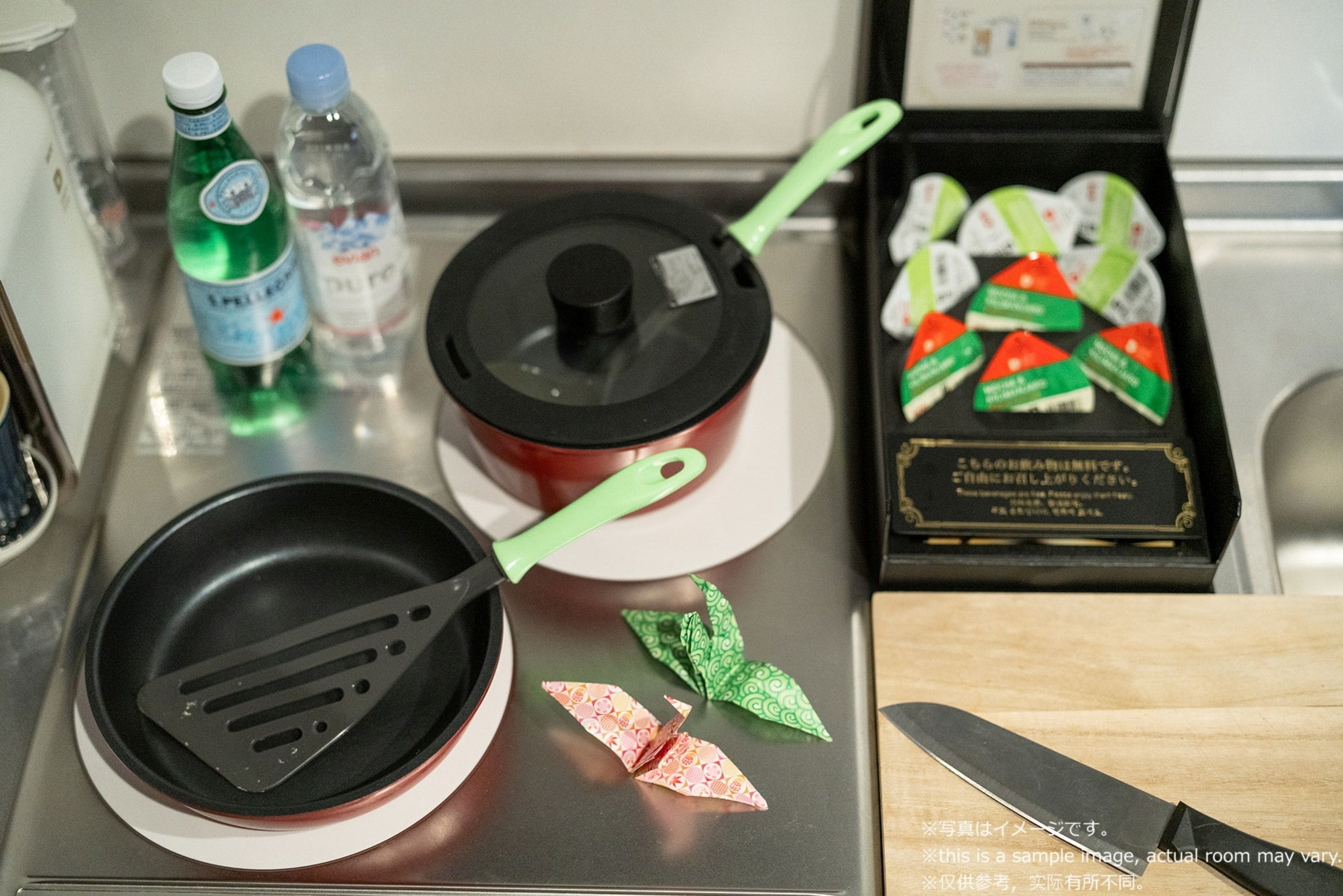 Un plan de travail de cuisine avec une poêle, une spatule, des bouteilles d’eau, une casserole et des aliments emballés.
