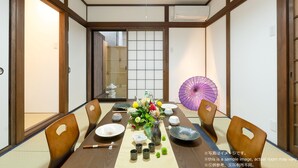 A traditional Japanese dining room with tatami mats, a low table, wooden chairs, and a purple umbrella. - Stay SAKURA Kyoto To-ji Machiya (Kyoto)