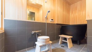 Ein modernes Badezimmer mit Holzvertäfelung, einer Badewanne, einer Toilette und einer Dusche.