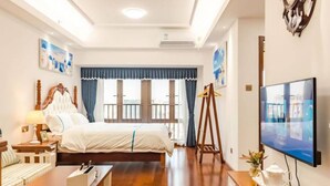 Ein Hotelzimmer mit einem großen Bett, einem Schreibtisch, einem Fernseher und einem Fenster mit Vorhängen.