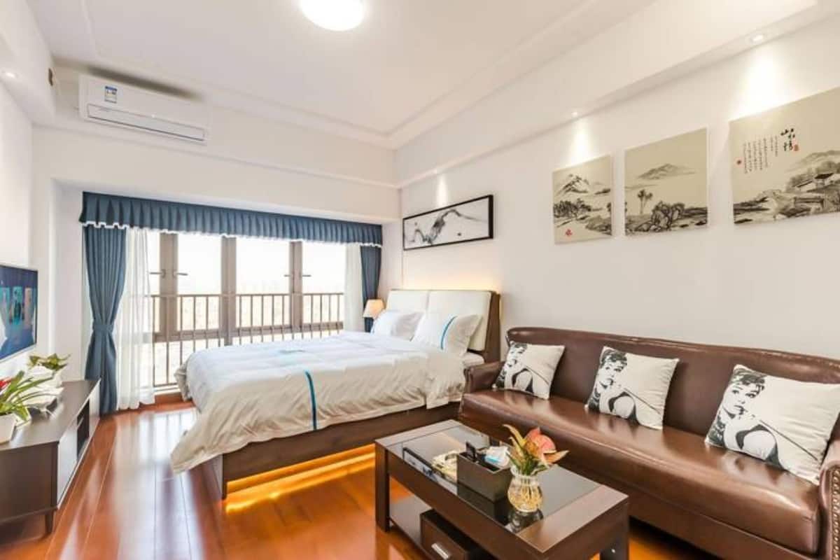 A hotel room with a bed, a brown leather sofa, a coffee table, and artwork on the wall.