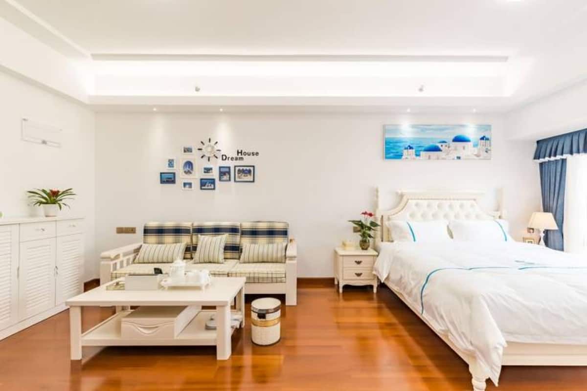 A modern bedroom with a bed, a sofa, a bedside table, and a small table with a lamp.