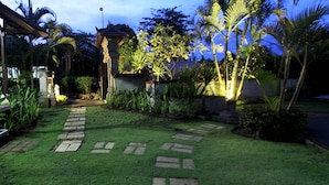 A well-maintained garden with a stone pathway, palm trees, and a gazebo. - Alamanda (Pecatu)