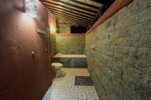 Bathroom features a bathtub, shower, and toilet, with a warm, earthy tone on the walls and a geometric tile floor.