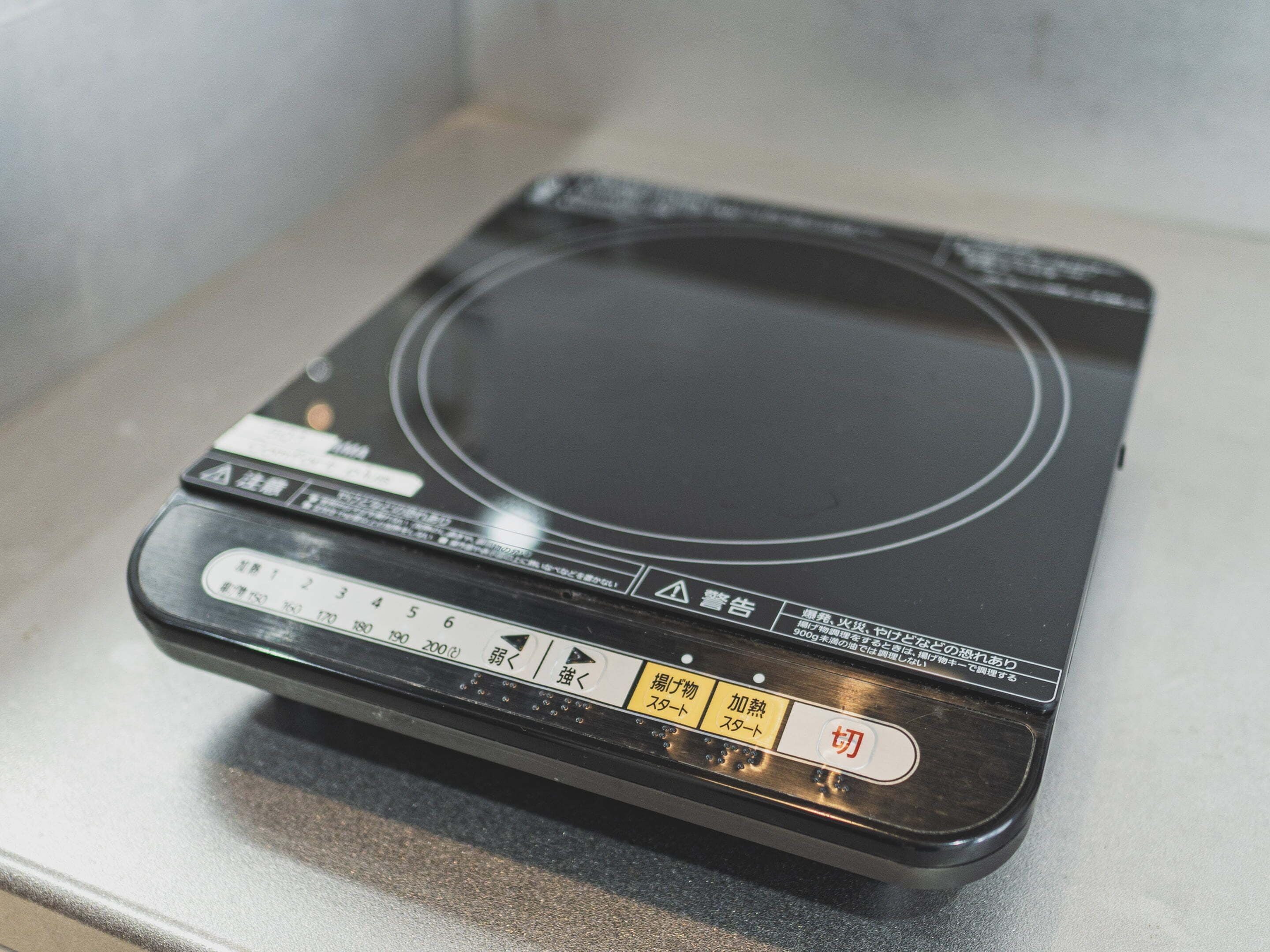Una placa de cocina por inducción negra con botones de control y una pantalla digital.
