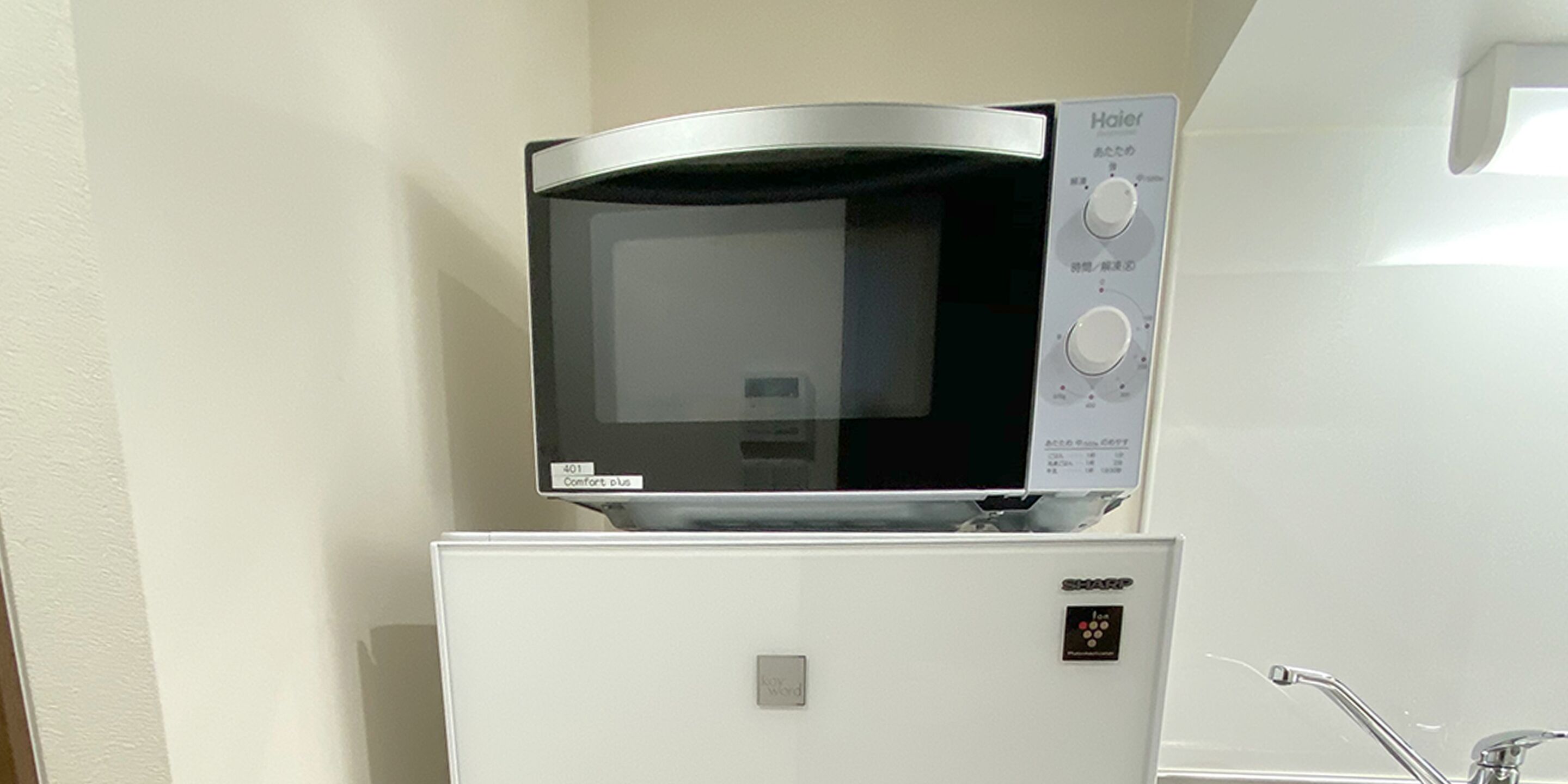 A microwave oven on top of a refrigerator in a kitchen.