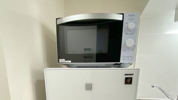 A microwave oven on top of a refrigerator in a kitchen.