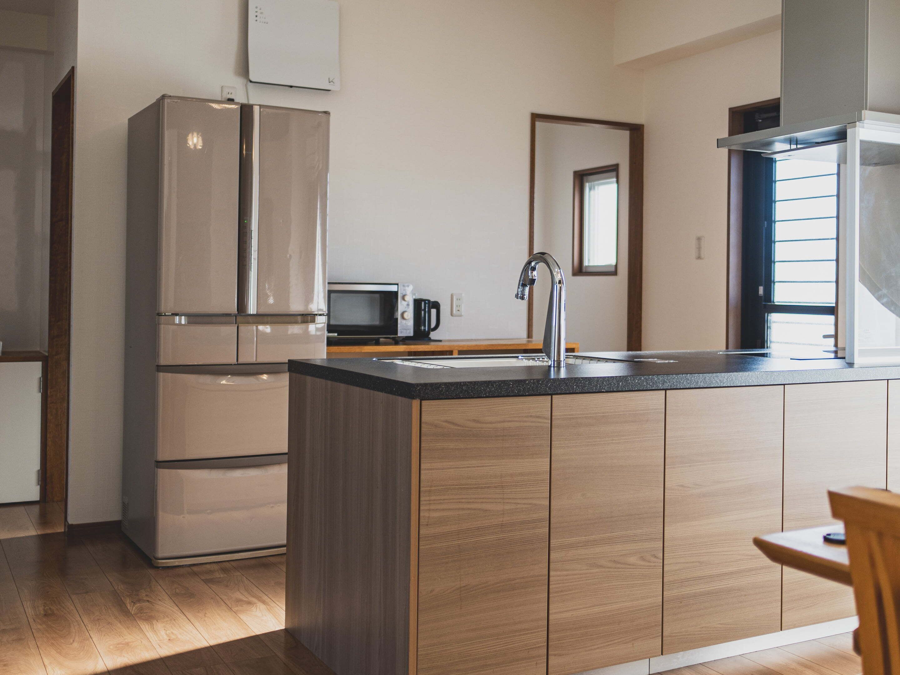 Une cuisine moderne dotée d’un îlot central, d’appareils électroménagers en acier inoxydable et de meubles de rangement en bois.