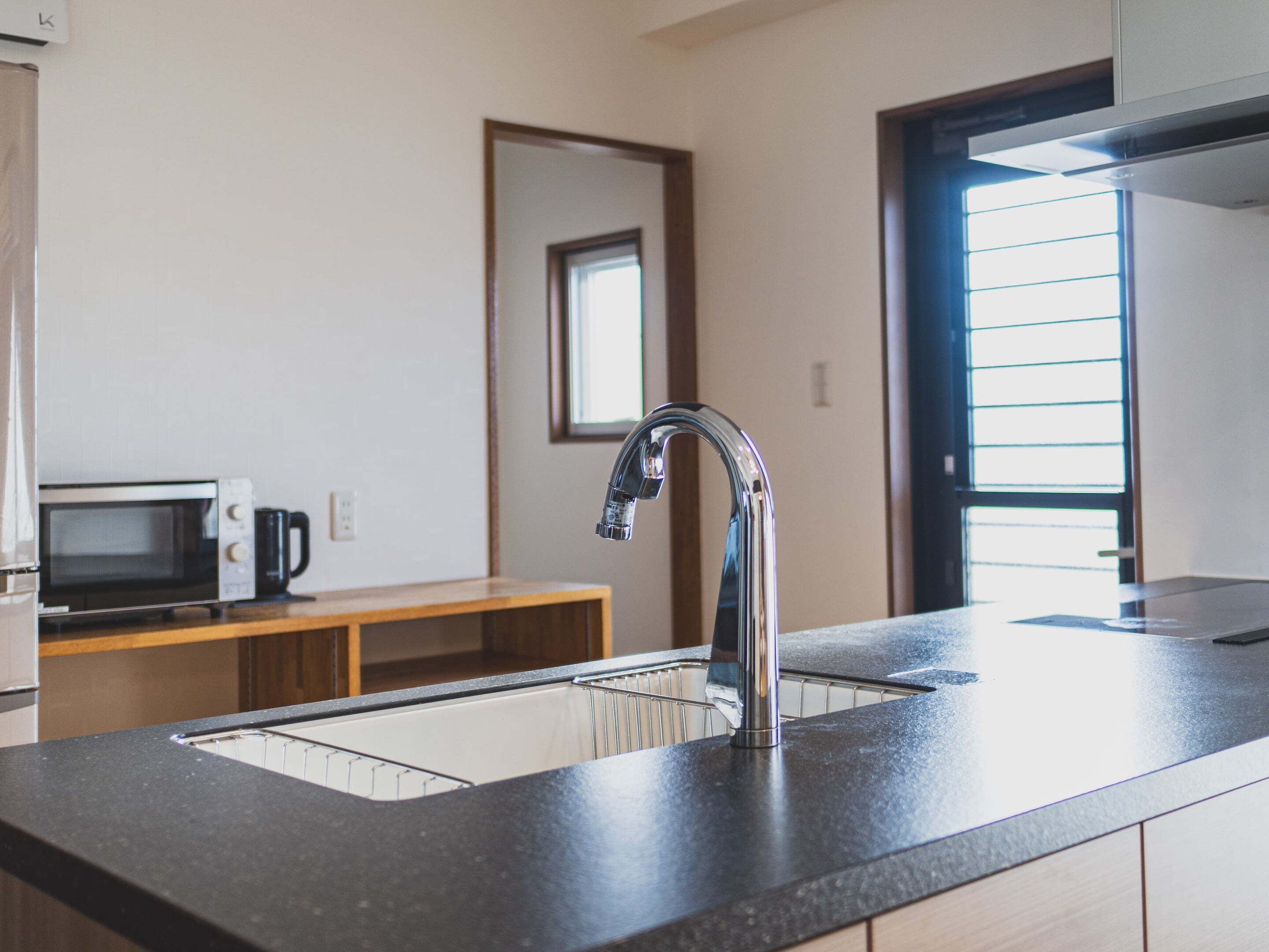 A modern kitchen with a stainless steel sink, a microwave, and a coffee maker on a wooden countertop.