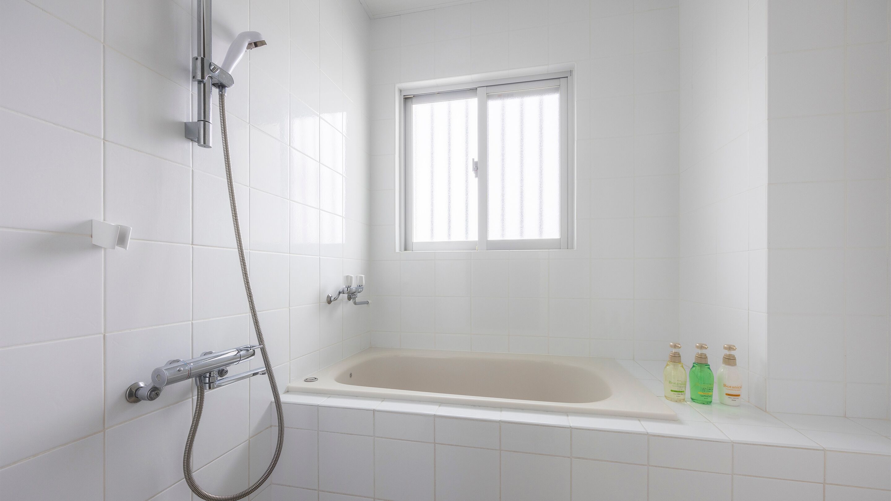 A bathroom with a bathtub, a shower, and a window.