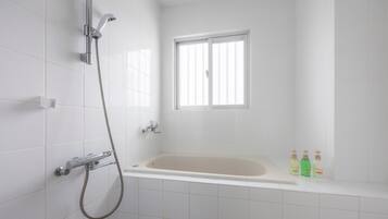 A bathroom with a bathtub, a shower, and a window.